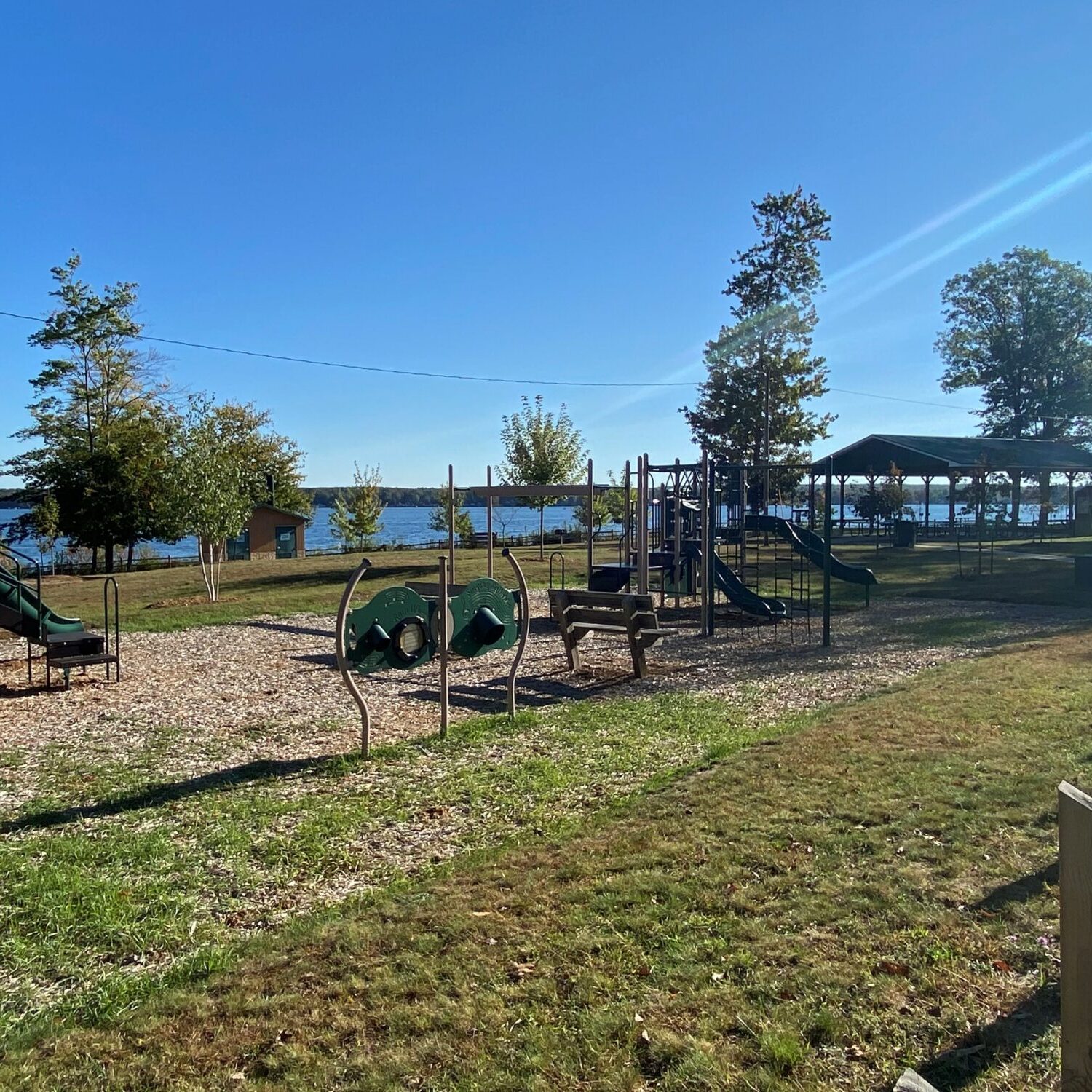 Playground by a lakeside park under clear blue sky.